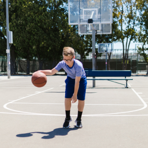 child playing basketball alone on a court