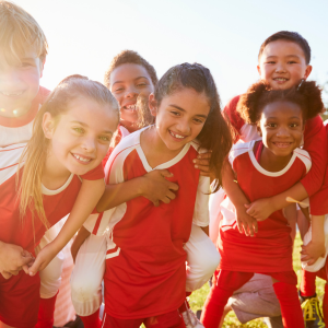 group of children wearing red sports kit playing in the sunshine