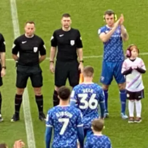 people from two football teams, adults and children, some with ear defenders some without