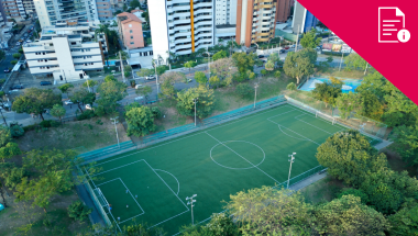 a sports court in an urban area, surrounded by trees, a small haven amongst the high rise. Red information graphic in corner