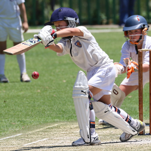 two children playing cricket on a grass pitch