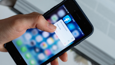 close up of a hand holding a phone using facebook