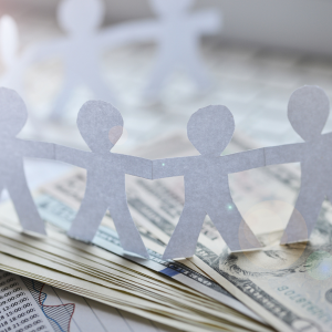 paper chain of stick figures standing on a pile of bank notes