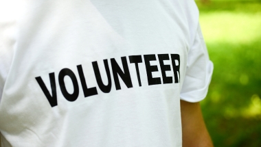 close up of a person wearing a white t shirt with volunteer written in black bold text